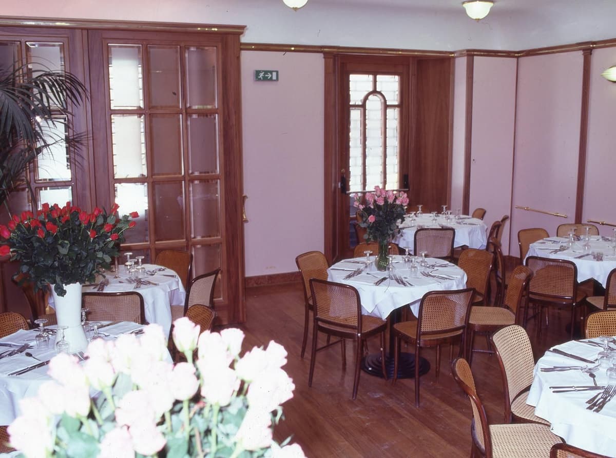 Private dining room with round tables, elegant seating, and floral decorations in a classic Italian restaurant.